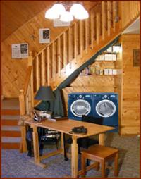 Drape is tied back, optional laundry is shown (simulated), with full-size washer and dryer, and aditional storage under landing to the left and on shelves above